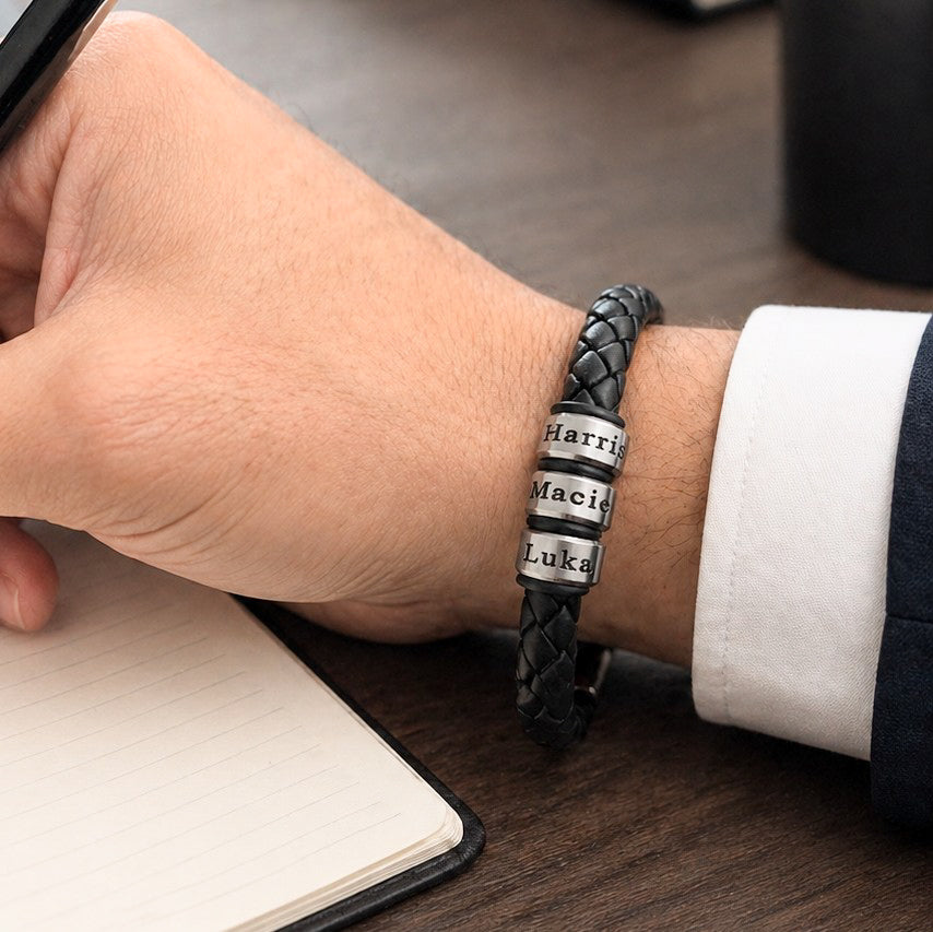 Man wearing black braided leather bracelet with engraved stainless steel name rings