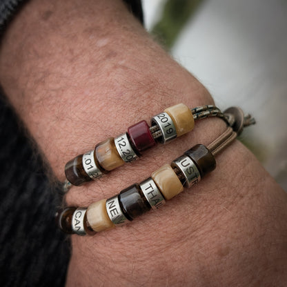 Men’s cord bracelets with custom engraved date beads worn on the wrist