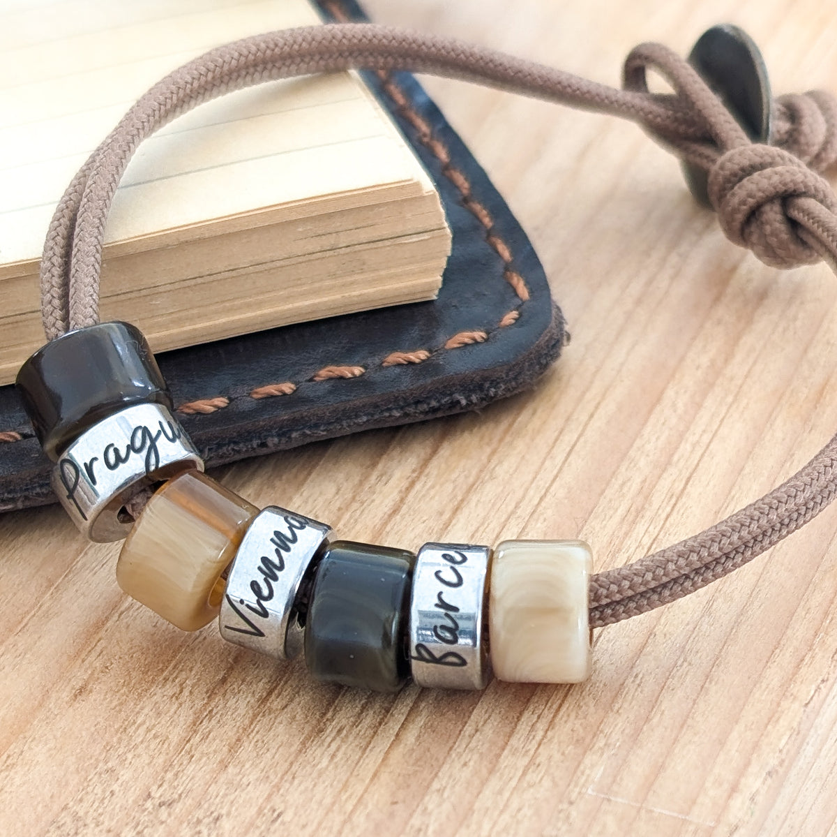 Men’s cord bracelet with engraved travel beads and personalised place names