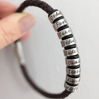 Close-up of personalised men's leather bracelet with multiple engraved stainless steel name rings
